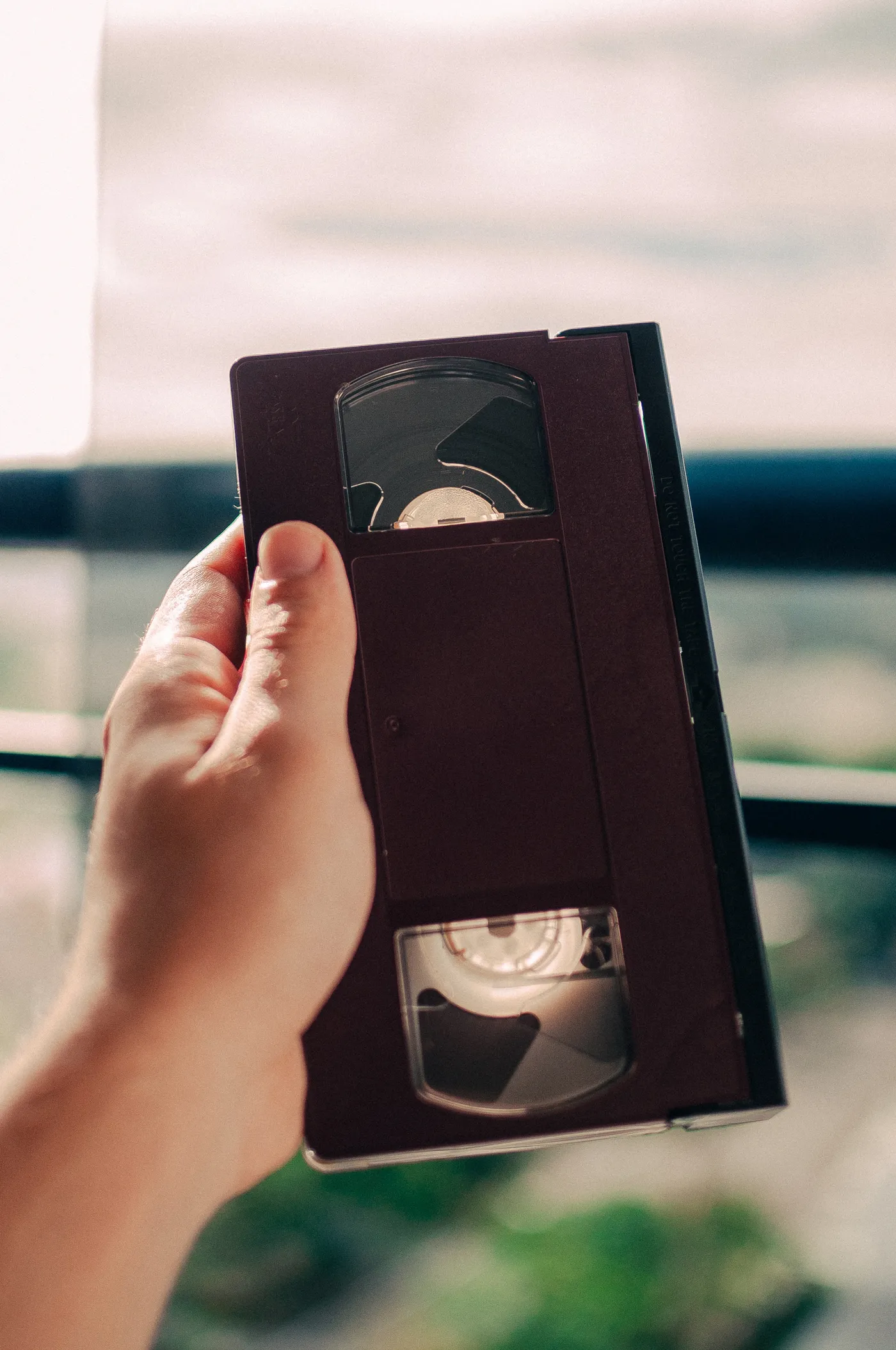 A hand holding a VHS tape up to the light